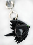 Black alien hand keychain with green finger on a white background