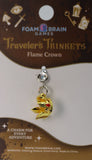 Gold flame-shaped charm on a 'Traveler's Trinkets' card with Foam Brain Games branding.