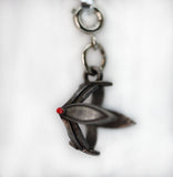 Metallic pendant with a red gemstone on a white background