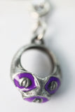 Metallic keychain with purple accents on a white background