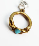 Gold pendant with a turquoise stone on a white background