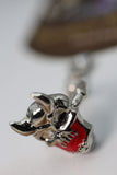 Close-up of a silver and red pendant on a blurred background