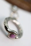 Silver ring with a pink stone on a blurred background