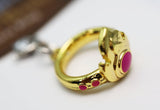 Gold ring with red gemstones on a white background