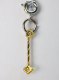 Gold key-shaped charm with a heart at the bottom on a gray background