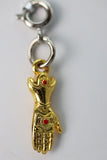 Gold hand charm with red gem on a white background