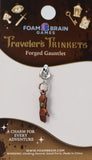 Foam Brain Games Traveler's Trinkets Forged Gauntlet charm on a brown card with branding and product details.
