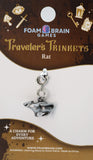 Charm for 'Traveler's Trinkets' by Foam Brain Games on a display card with decorative elements.