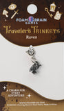 Silver charm on a Foam Brain Games 'Traveler's Trinkets' card with branding and product details.