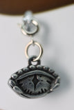 Silver eye-shaped pendant on a blurred background