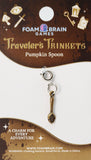 Pumpkin spoon charm on a Foam Brain Games packaging with decorative elements.