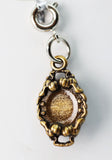 Gold and silver charm with a textured center on a white background