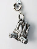 Silver charm of a hand holding a stick on a white background