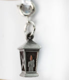 Silver lantern charm with a candle inside on a white background