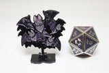 Black and purple bat-themed collectible with a metal die on a white background