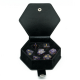 Set of polyhedral dice with purple and gold numbers in a black hexagonal container on a white background