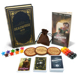 Deadwood 1876 game components including book, cards, dice, and tokens on a white background
