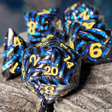 Set of blue and silver polyhedral dice with yellow numbers on a textured surface.