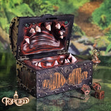 Decorative chest with monster face design on a table with gaming accessories.