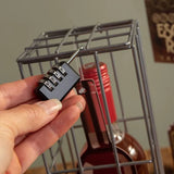 Hand holding a combination lock in front of a metal cage with a red bottle inside.