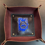 Brown leather tray with blue and white design on a metallic surface