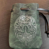 Green leather pouch with intricate white design on a brown surface