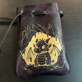 Dark leather pouch with gold dragon design on a dark surface