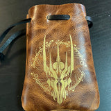 Brown leather pouch with engraved design on a dark surface