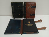 Four leather-bound books with visible branding on a white surface