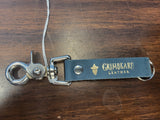 Keychain with metal clip on a wooden surface, featuring 'Gribeard Leather' branding.