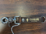 Brown leather keychain with metal clasp on a wooden surface, featuring 'Grainbeard Leather' branding.