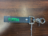Keychain with green logo and silver clasp on a wooden surface