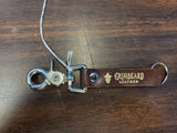 Brown leather keychain with metal clasp on a wooden surface, featuring 'Grimbeard Leather' branding.