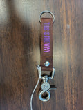 Brown leather keychain with 'THIS IS THE WAY' text on a wooden surface