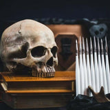 Skull on books with a hand holding daggers in a dark setting