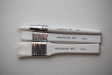 Three paintbrushes with labels on a gray background