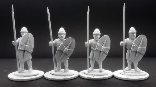 Four white plastic figurines of soldiers with spears and shields on a black background