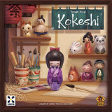 Board game box for 'Kokeshi' with illustrated characters and tools on a wooden shelf.