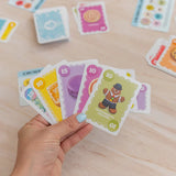 Hand holding colorful card game cards on a wooden surface