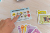 Card game with 'Crumb Collector' card and other cards on a table.