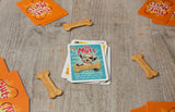 Stack of dog-themed cards on a wooden surface with bone-shaped treats.