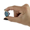 A hand with dark nail polish holds a small Beyblade toy against a plain white background.