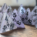 Set of clear polyhedral dice with numbers and symbols on a wooden surface