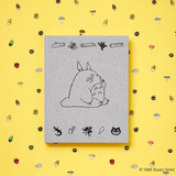 Notebook with Totoro illustration on a yellow background with small illustrations of mushrooms and other objects.