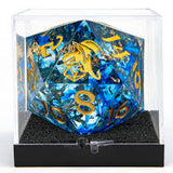 Large polyhedral dice with blue and gold colors in a clear display case.