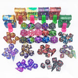 Assorted colorful polyhedral dice set with treasure chest containers on a white background