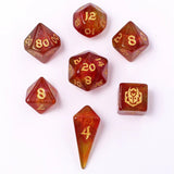 Set of red and gold polyhedral dice with gold numbers on a white background