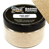 Container of 'Huge Miniatures' fine grit material with a black lid.