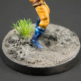 Miniature figure on a round base with textured surface and grass-like plant