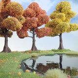 Three trees with colorful foliage reflected in a pond with a clear blue sky.